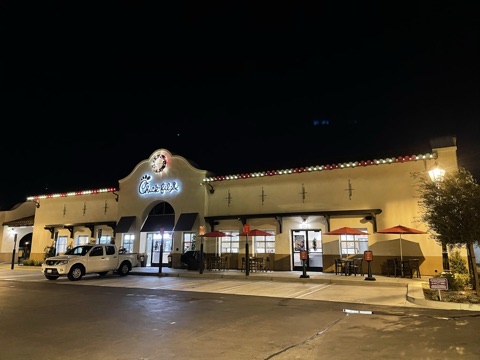 Wide nighttime view of a Chick-fil-A restaurant decorated with Christmas roofline lights