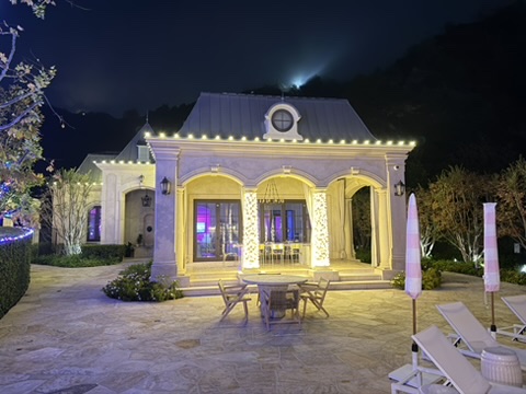 Garden pavilion with warm-white roofline and column lights around an outdoor seating area